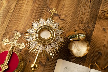 Catholic religion symbols. The Cross, monstrance, Holy Bible and golden chalice on the rustic wooden table.の写真素材