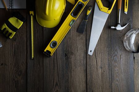 Contractor concept. Tool kit of the contractor: yellow hardhat, libella, hand saw, and notebook on...