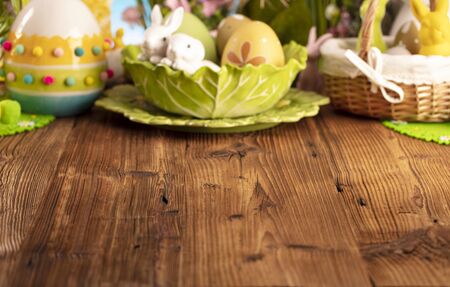 Happy Easter background. Bouquet of spring flowers. Easter decorations and Easter eggs in basket on rustic wooden table.の写真素材