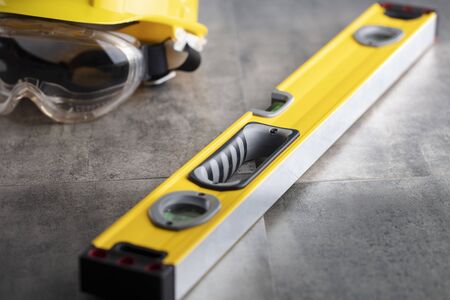 Contractor concept. Tool kit of the contractor: yellow hardhat, libella, hand saw. Plans and...