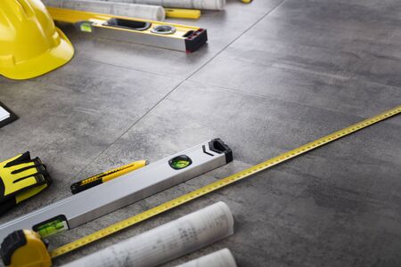 Contractor concept. Tool kit of the contractor: yellow hardhat, libella, hand saw. Plans and...