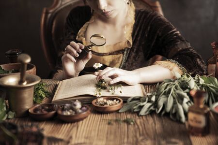 Natural medicine concept. Vintage pharmacist preparing natural medicament. Brass mortar and  bottles. Rustic table. Assorted dry herbs in bowls.の写真素材