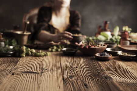 Natural medicine concept. Vintage pharmacist preparing natural medicament. Brass mortar and  bottles. Rustic table. Assorted dry herbs in bowls.の写真素材