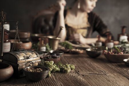 Natural medicine concept. Vintage pharmacist preparing natural medicament. Brass mortar and  bottles. Rustic table. Assorted dry herbs in bowls.の写真素材