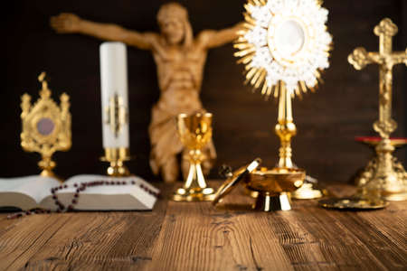 Catholic religion symbols. The Cross, monstrance, Jesus figure, Holy Bible and golden chalice on the rustic wooden altar.の写真素材