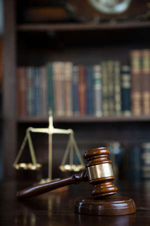 Law theme. Judge chamber. Gavel and scale on brown shining desk. Collection of legal books in the...