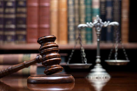 Law theme. Judge chamber. Judgeâ€™s gavel on brown shining desk. Collection of legal books in...