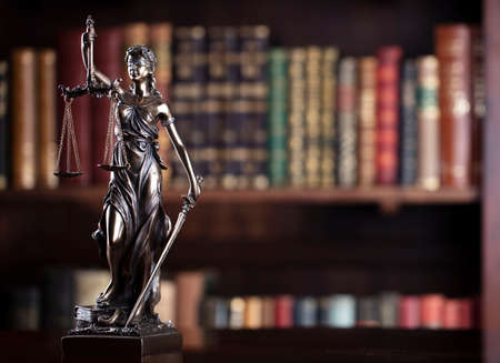 Law and justice concept. Themis sculpture in lawyers office. Bookshelf with legal books in...