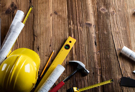Contractor office. Tool kit of the contractor: yellow hardhat, libella. Plans and blueprints on the...
