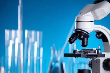 Science concept. Laboratory equipment composition. Test tubes and microscope on blue background.