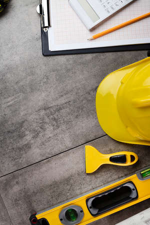 Contractor concept. Tool kit of the contractor: yellow hardhat, libella, hand saw. Plans and...
