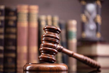 Law theme. Judge chamber. Judgeâs gavel and collection of legal books on the brown desk and the brown background.の写真素材