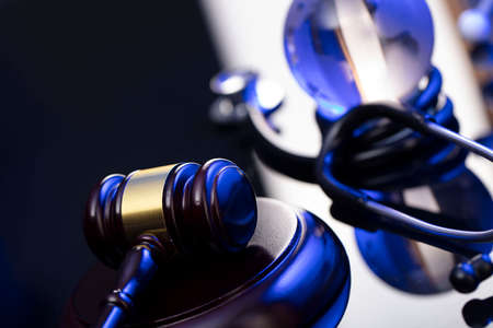 Medical law concept. Gavel and stethoscope on the glass table. Blue light.の写真素材