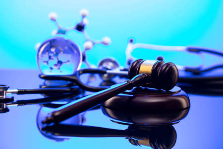 Medical law concept. Gavel and stethoscope on the glass table. Blue light.の写真素材
