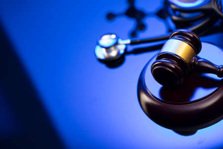 Medical law concept. Gavel and stethoscope on the glass table. Blue light.