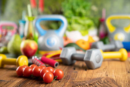 Fitness concept. Healthy nutrition: fruits and vegetables. Equipment for fitness exercises: weighing machine and dumbbells.の写真素材