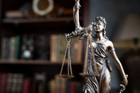 Justice concept. Judge chamber. Themis statue on brown shining desk.の写真素材