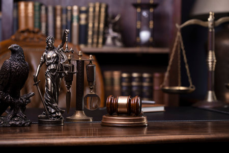 Law and justice theme. Judge chamber. Themis statue, gavel and scale on brown desk. Legal books in the bookshelf as background.の写真素材