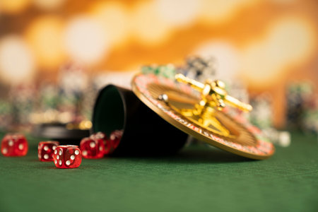 Casino concept.  Roulette wheel, poker chips and dice on green table and on  yellow bokeh background.の写真素材