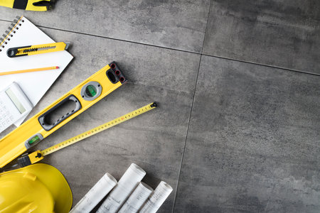 Contractor concept. Tool kit of the contractor: yellow hardhat, libella, hand saw. Plans and...