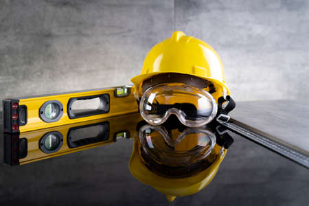 Contractor concept. Tool kit of the contractor: yellow hardhat, libella and tools on the gray...