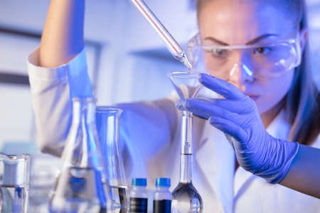 Laboratory concept background. Young scientist during experiment and using microscope in modern...