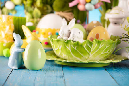 Easter theme. Easter decorations. Easter eggs in basket and cabbage leaf. Bouquet of spring flowers. Blue background.の写真素材