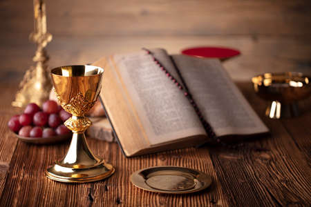 Catholic religion concept. Catholic symbols composition. The Cross, Holy Bible and golden chalice on the altar.の写真素材