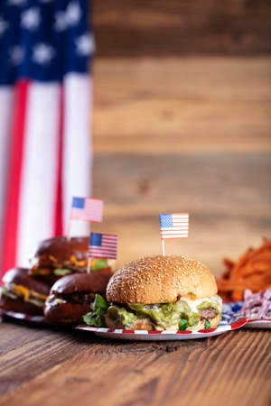 Fourth of July celebration. American flag and decorations. Burgers on rustic wooden table.の写真素材