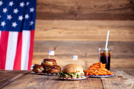 Fourth of July celebration. American flag and decorations. Burgers on rustic wooden table.