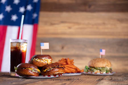 Fourth of July celebration. American flag and decorations. Burgers on rustic wooden table.の写真素材