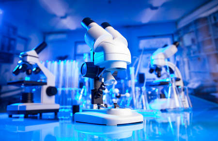Laboratory investigations concerning covid pandemy. Microscope, glass tubes and beakers in the...