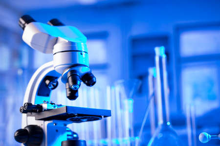 Laboratory investigations concerning covid pandemy. Microscope, glass tubes and beakers in the...