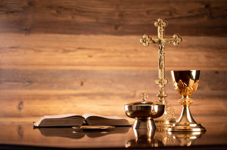 Catholic religion concept. Catholic symbols composition. The Cross, monstrance,  Holy Bible and golden chalice on brown background.の写真素材