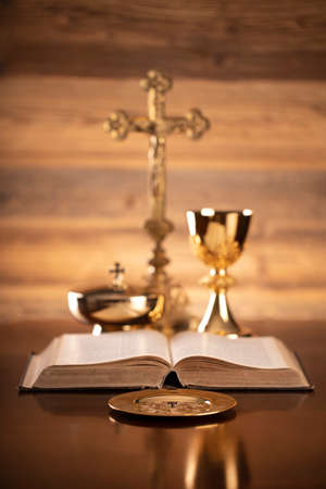 Catholic religion concept. Catholic symbols composition. The Cross, monstrance,  Holy Bible and golden chalice on brown background.の写真素材