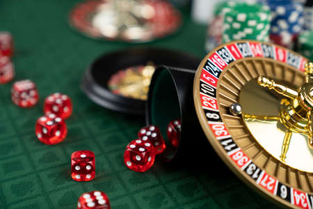Casino. Gambling games theme.  Roulette wheel, dice and poker chips on the casino felt green table.の写真素材