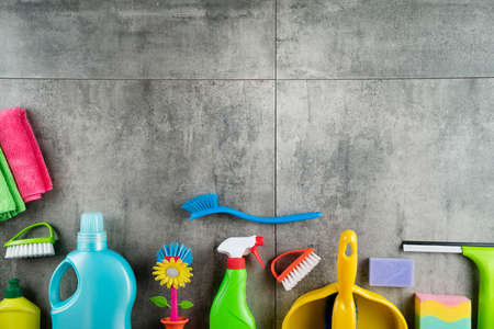 Autumn cleaning. Colorful set of bottles with clining liquids and colorful cleaning kit on gray tiles.の写真素材