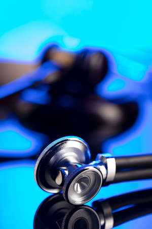 Medical law concept. Gavel, Themis, legal code and stethoscope on the glass table. Blue light.の写真素材