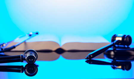 Medical law concept. Gavel, Themis, legal code and stethoscope on the glass table. Blue light.の写真素材