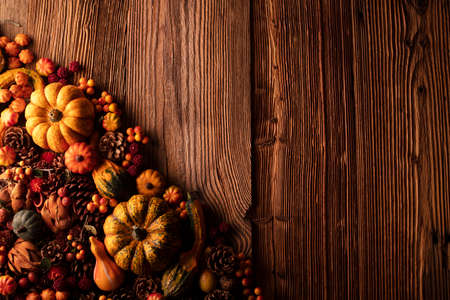 Autumn composition on a rustic wooden background. Decorative pumpkins, various leaves, pine cones, nuts. Orange, yellow, red  and brown aesthetics.の写真素材