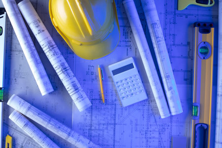 Architect and contractor concept. Tool kit of the contractor: yellow hardhat, libella. Plans and notebook on the desk.の写真素材