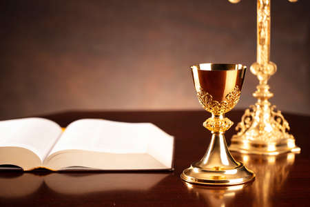 Catholic religion concept. The Cross,  Holy Bible and golden chalice on the altar.の写真素材
