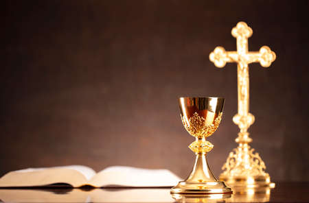 Catholic religion concept. The Cross,  Holy Bible and golden chalice on the altar.
