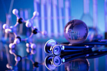 Laboratory investigations concerning test and medicine against covid. Microscope, shethoscope, glass tubes and beakers on blue background.の写真素材