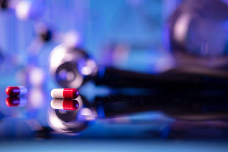 Laboratory investigations concerning test and medicine against covid. Microscope, shethoscope, glass tubes and beakers on blue background.の写真素材