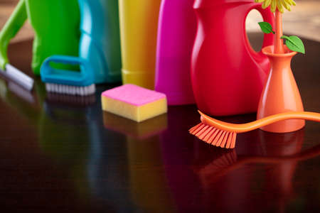 Autumn cleaning. Colorful set of bottles with clining liquids and colorful cleaning kit on brown...