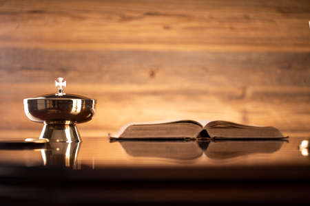 Catholic symbols composition. Religion concept. Holy Bible, rosary and golden chalice on the brown...