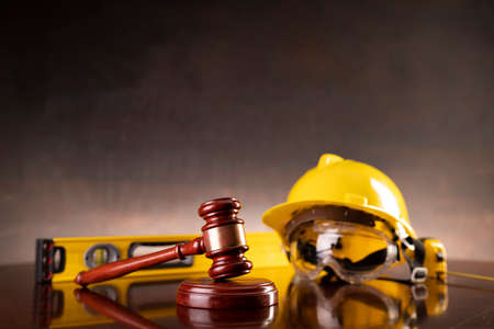 Labour law and builiding law concept.  Gavel and yellow crash helmet on the shining lawyer desk.の写真素材