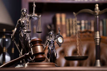 Judge office. Gavel, scale, Themis sculpture on the desk. Law books in the bookshelf.の写真素材