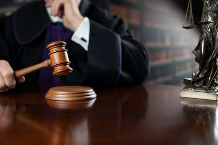 Judge in the courtroom. Judge with the wooden gavel in his hand. Law and justice theme.の写真素材